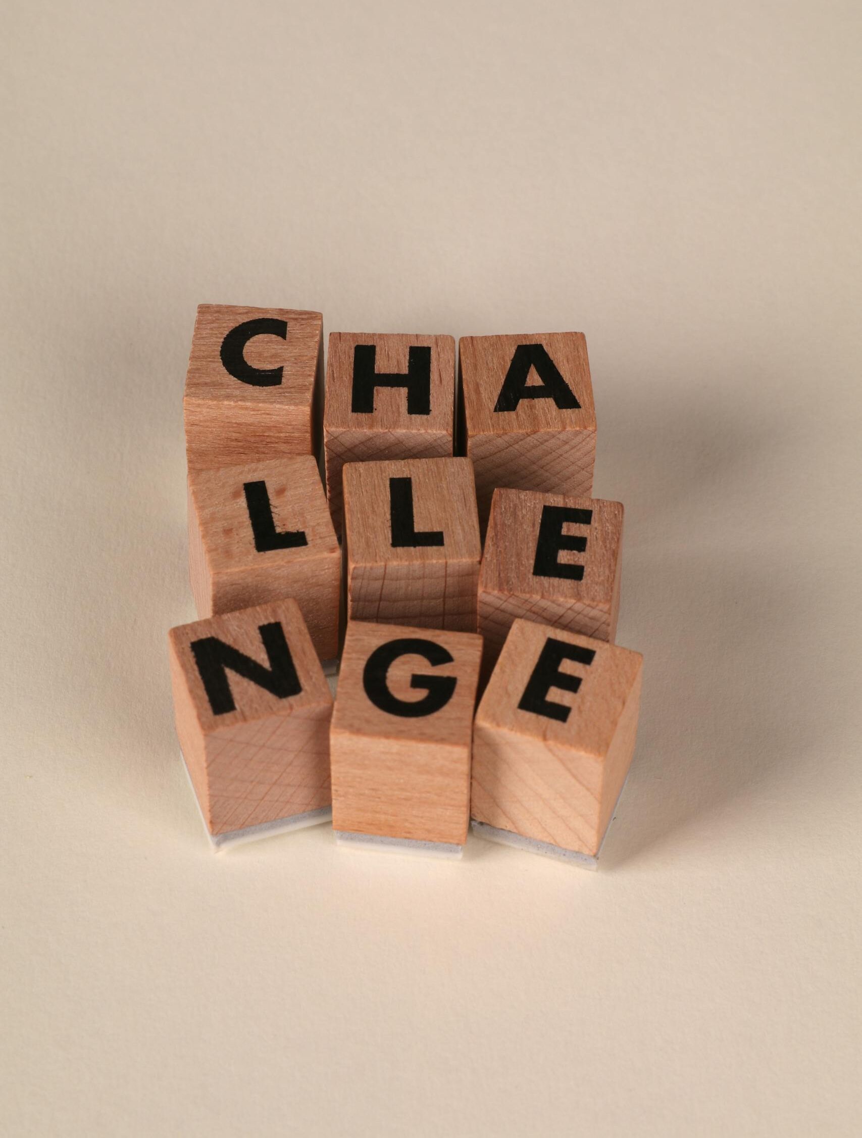 Wooden blocks forming the word 'CHALLENGE' symbolize problem-solving and strategy.
